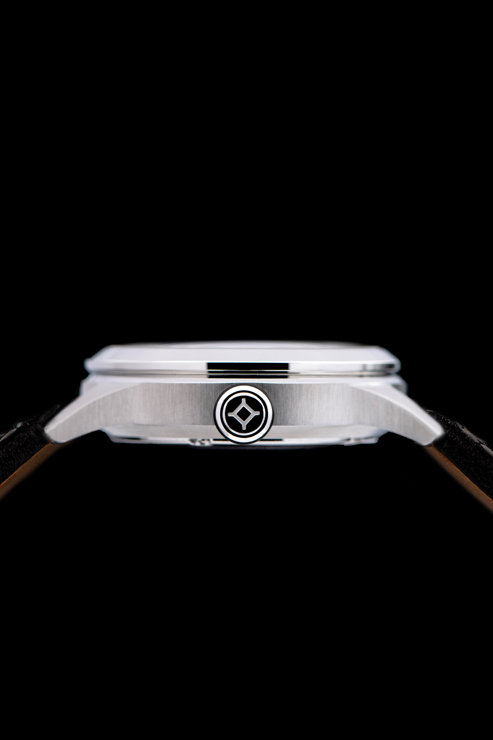 Gros plan sur le côté voir d'une montre-bracelet avec boîtier métallique, logo complexe et cuir bracelets sur fond noir.