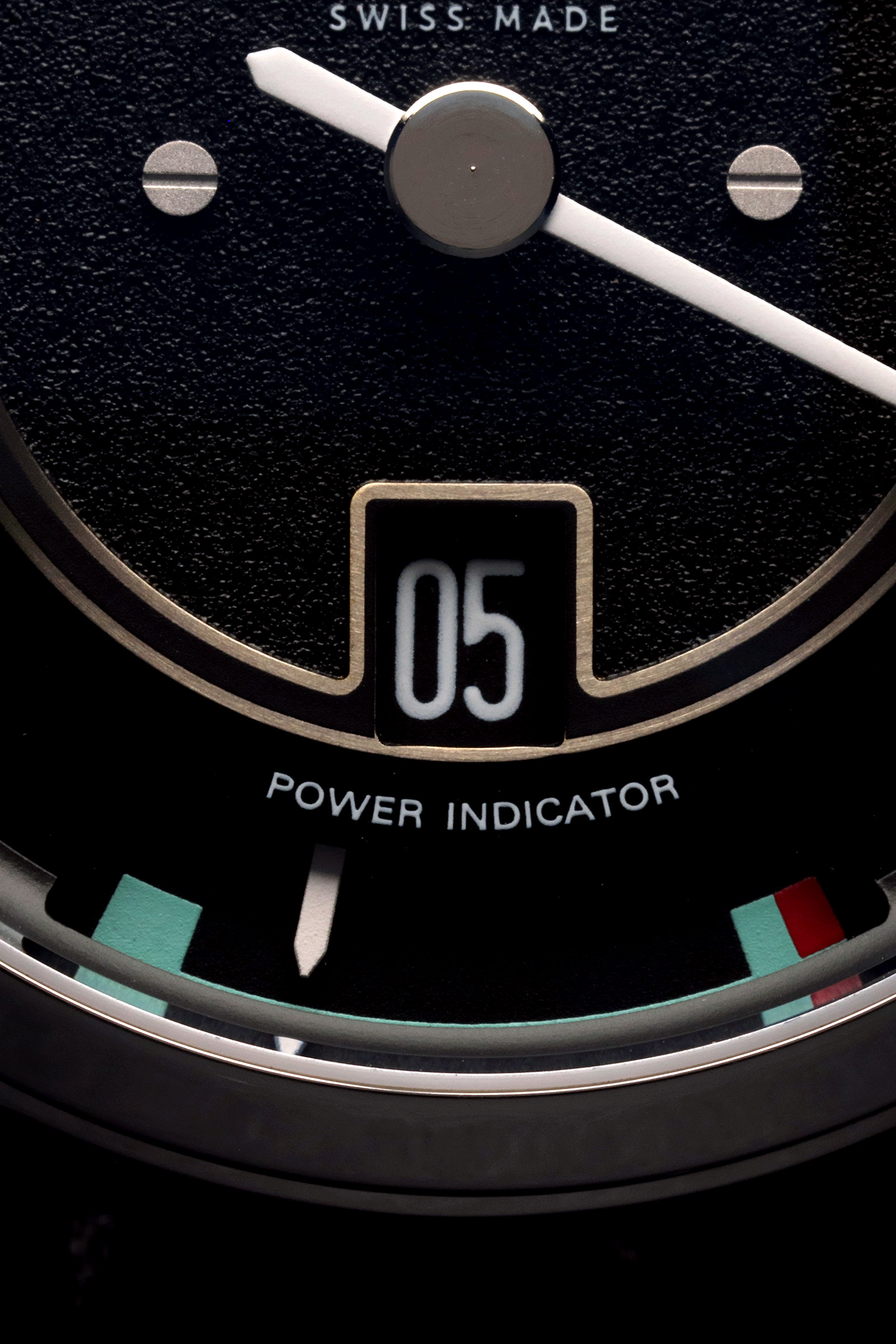 Gros plan d'un cadran de montre noir avec des aiguilles blanches, "POWER INDICATOR", "SWISS MADE" et le nombre "05".