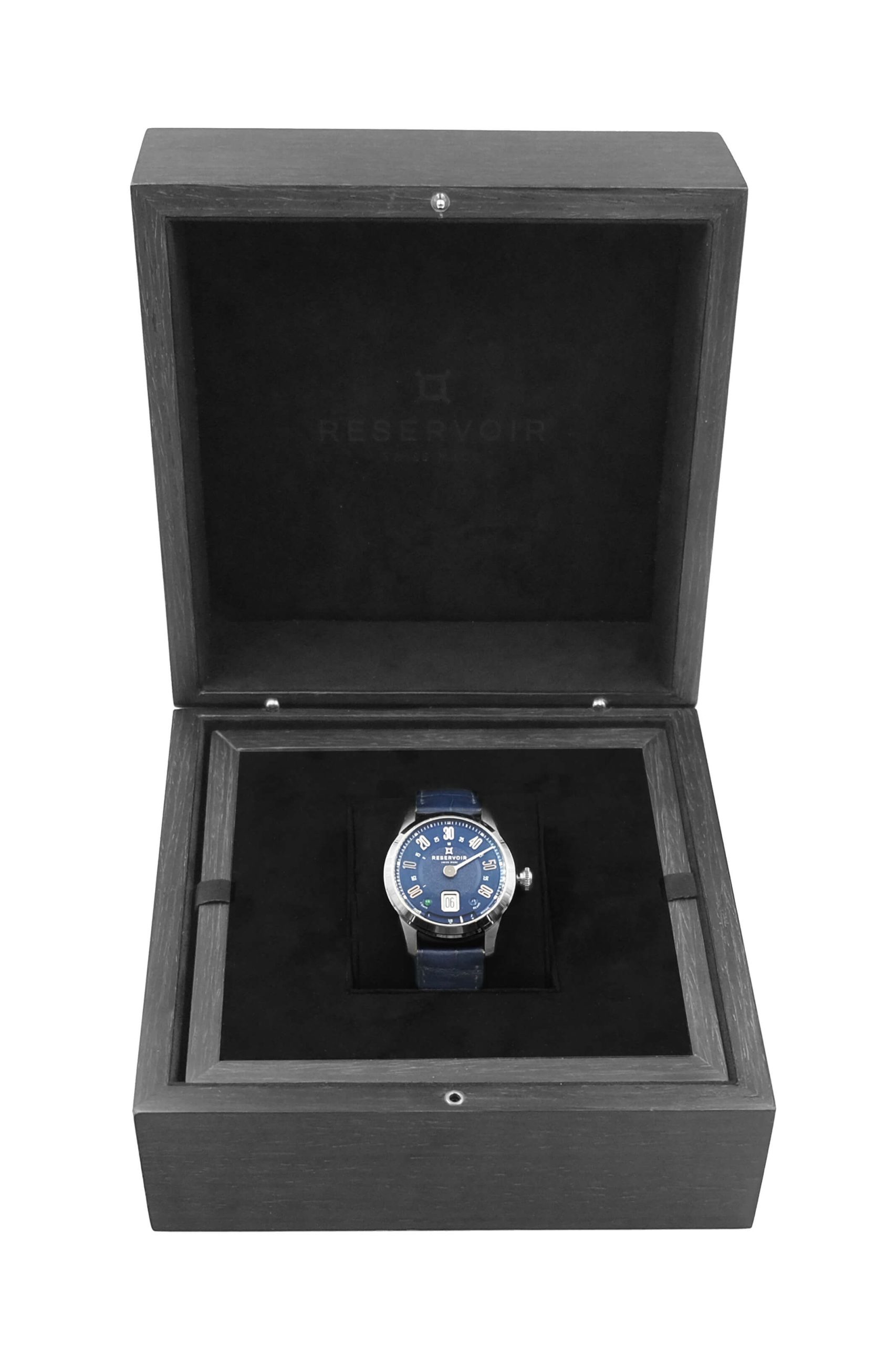 Reloj de pulsera con esfera y correa azules en caja de madera forrada de terciopelo negro.