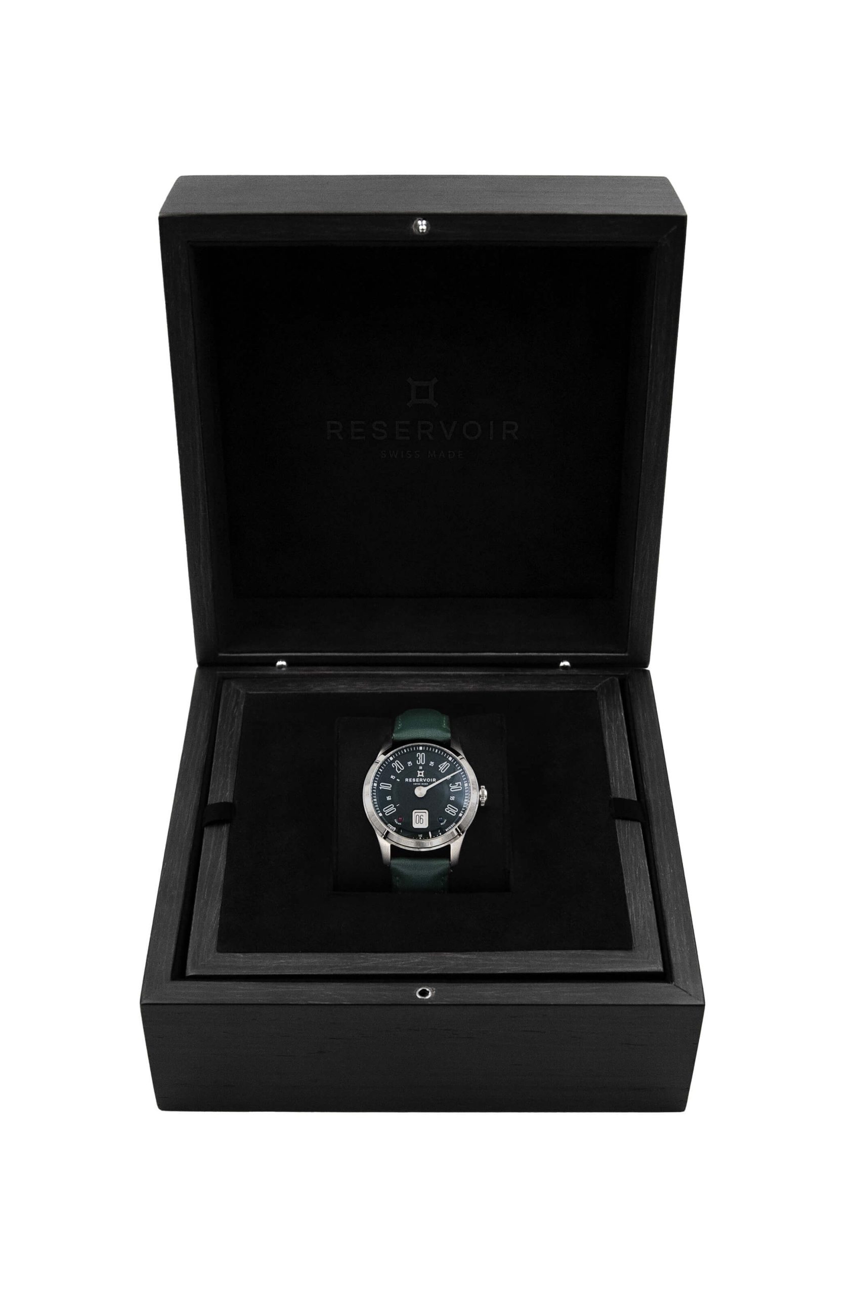 Montre-bracelet avec cadran foncé dans un boîtier ouvert en bois noir écrin avec inscription "RESERVOIR SWISS MADE".