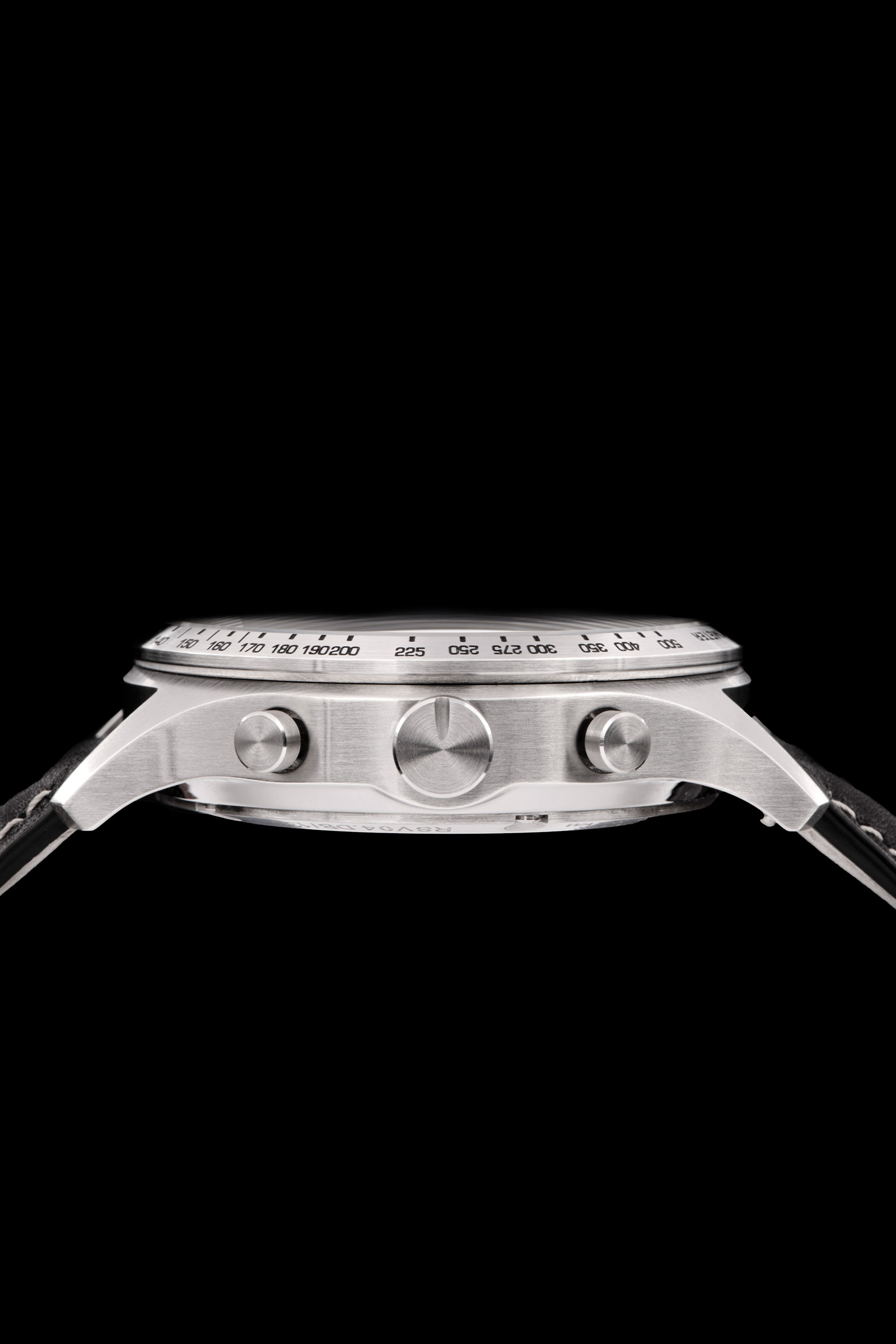 Close-up side view of a stainless steel wristwatch case with chronograph pushers and a black strap.