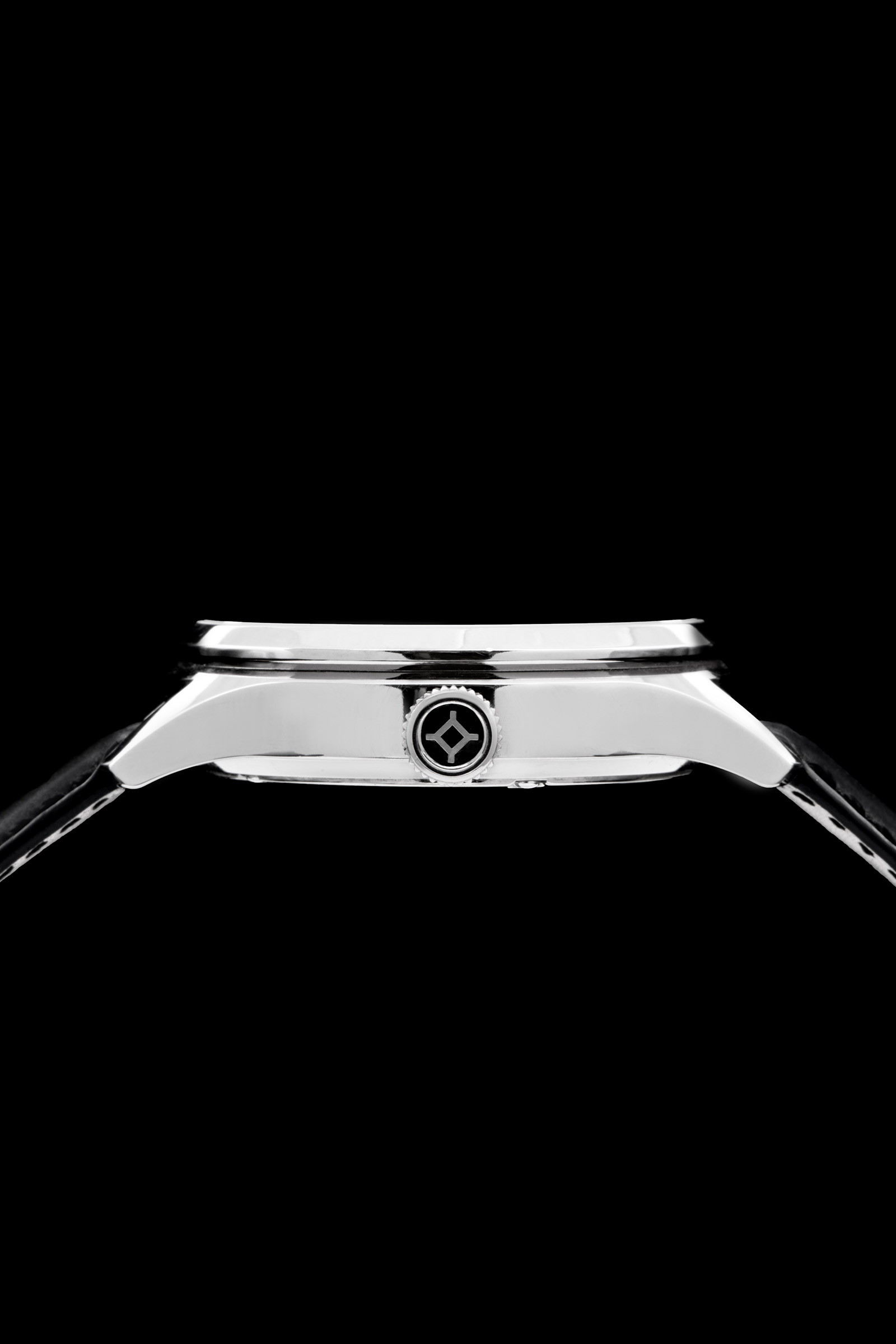 Close-up side view of a polished metallic wristwatch with emblematic crown on a black background.