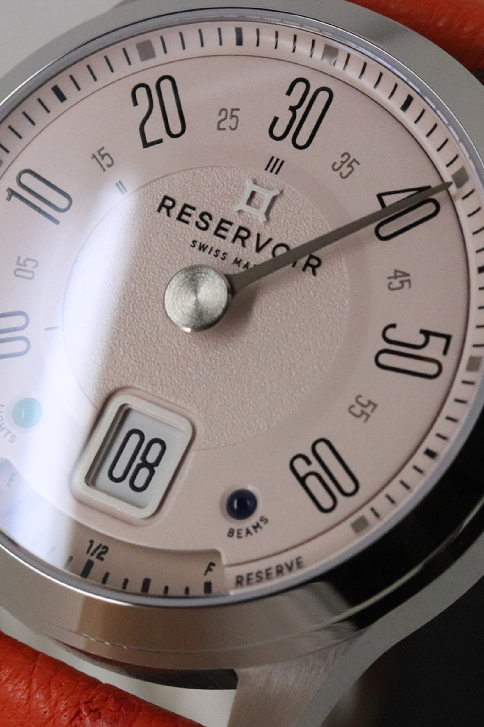 Montre-bracelet avec chiffres noirs, cadran auxiliaire, réserve de marche, cadre métallique et bracelet orange.