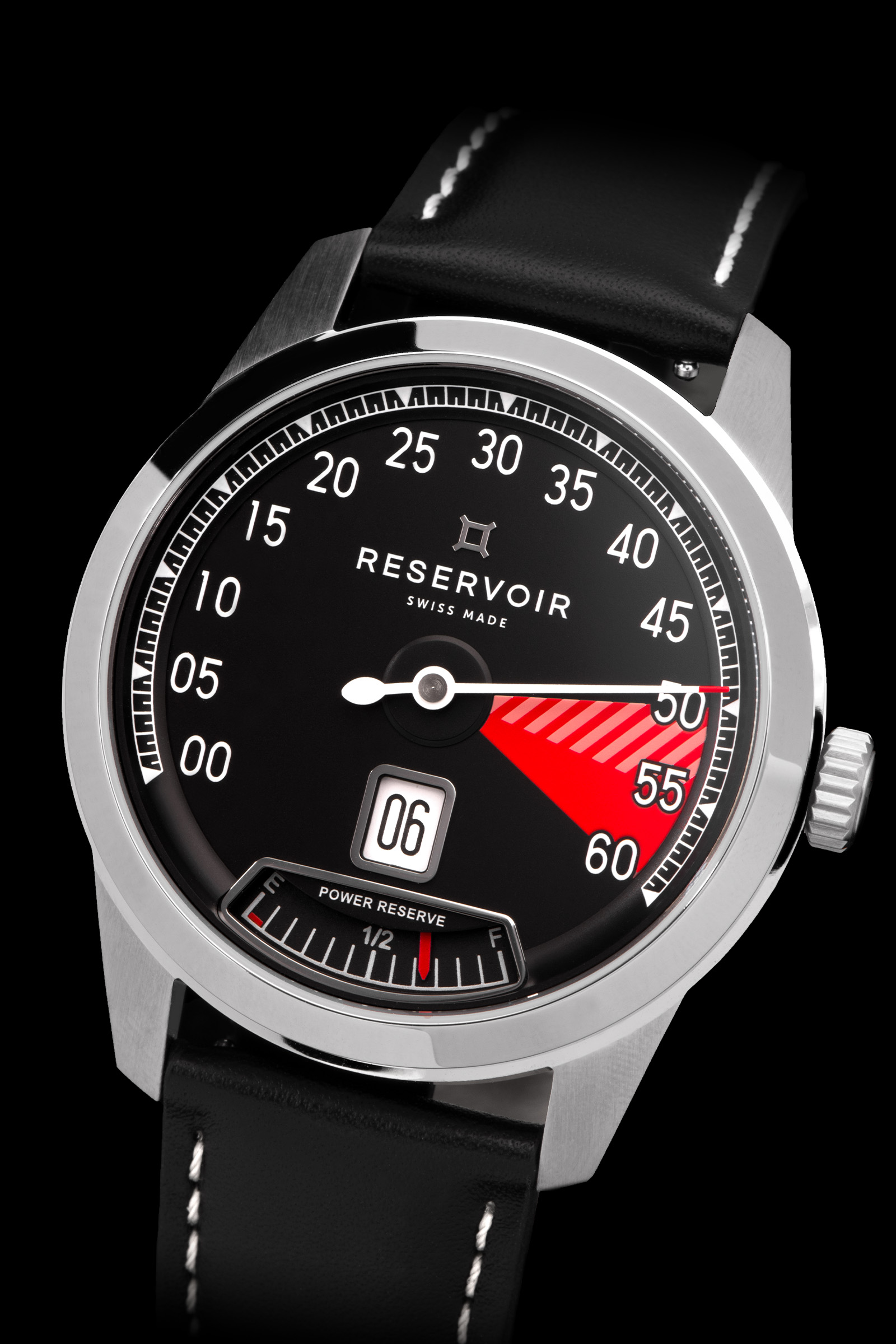 Reloj plateado con esfera negra, contador de 60 minutos, fecha (06), correa de piel e indicador de reserva de marcha.