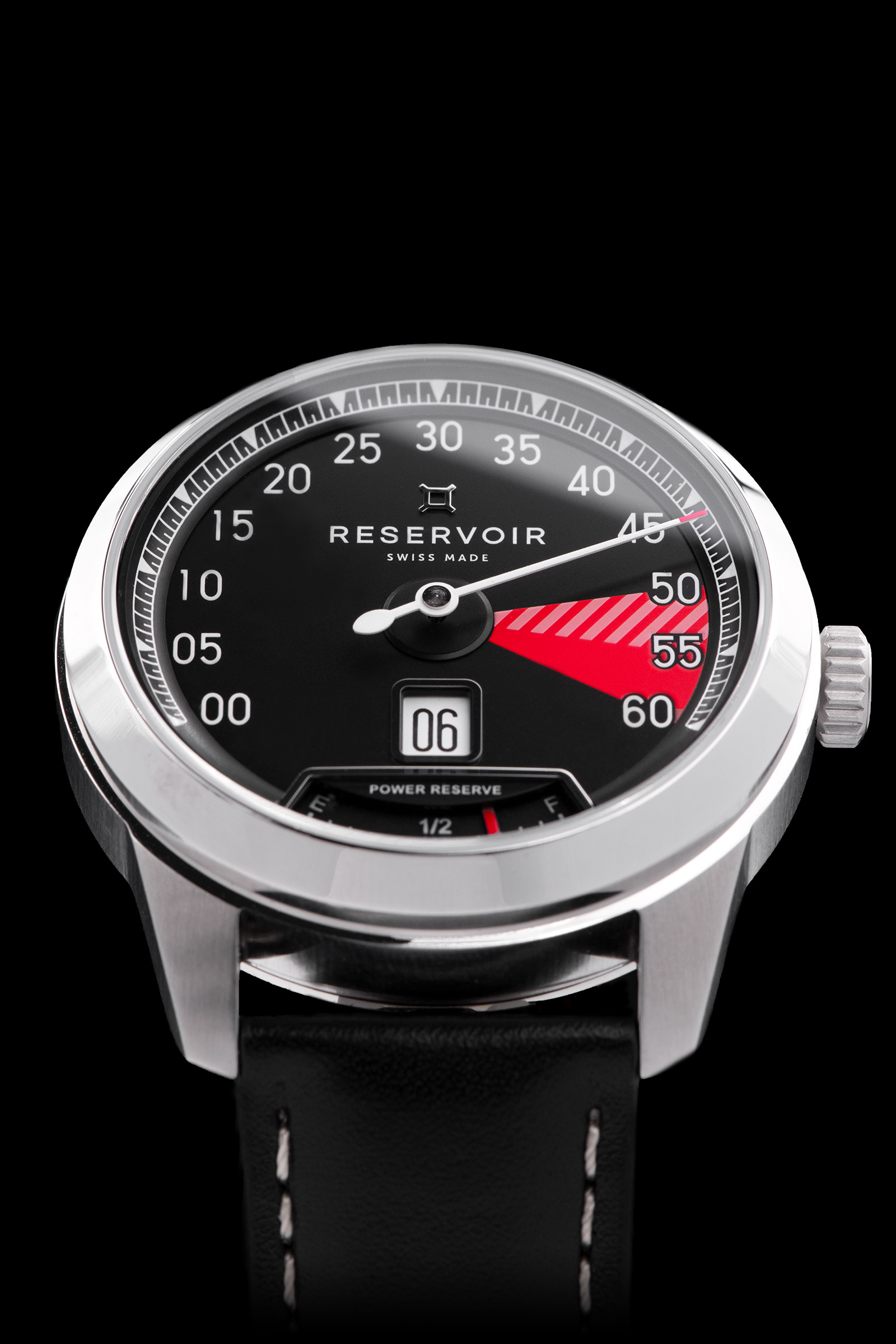 Reloj de pulsera con esfera negra, marcadores blancos y rojos, indicador de fecha, reserva de marcha, correa de piel negra.