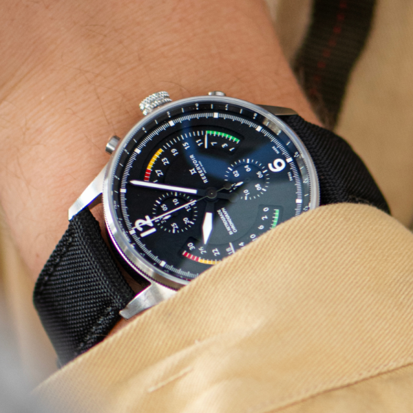 Wristwatch with black dial, colored accents, chronograph, sub-dials, and black fabric strap.