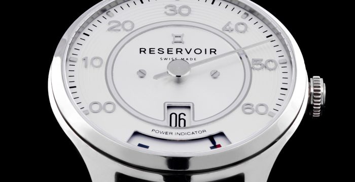Swiss-made wristwatch with silver casing, white dial, black leather strap, large numerals, and indicators.