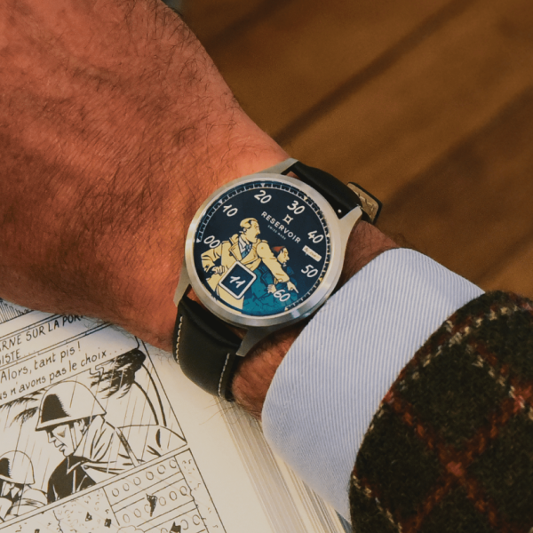 Person wearing a Reservoir wristwatch with unique artwork dial, over graphic novel or comic book.