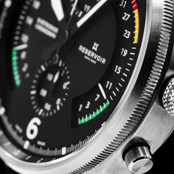 Close-up of a RESERVOIR wristwatch dial with colored indicators and a metallic casing.