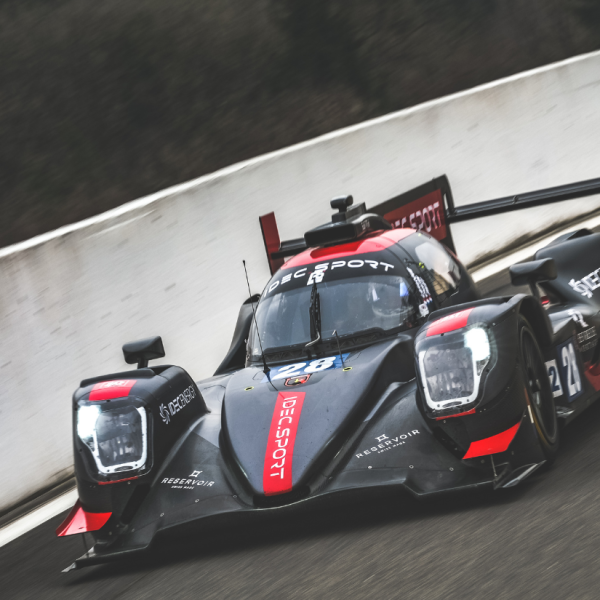 Sleek black and red racing car number 28 in motion on a track with blurred background