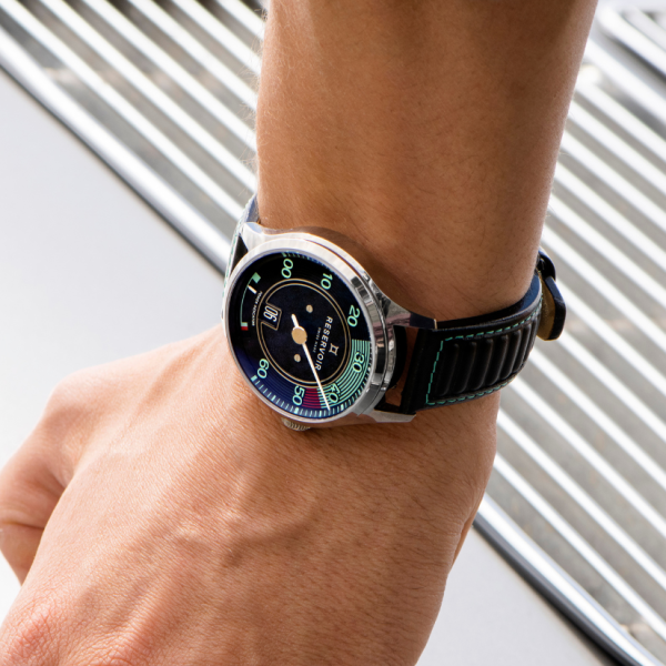 Wristwatch with black dial, single hand, minute scale, date window, metallic case, black stitched strap