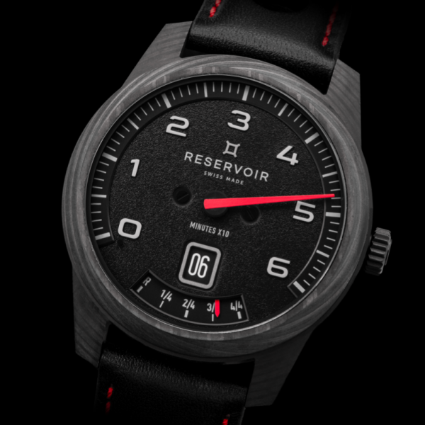 Wristwatch with black dial, white numerals, red second hand, date display, gauge-style indicator.