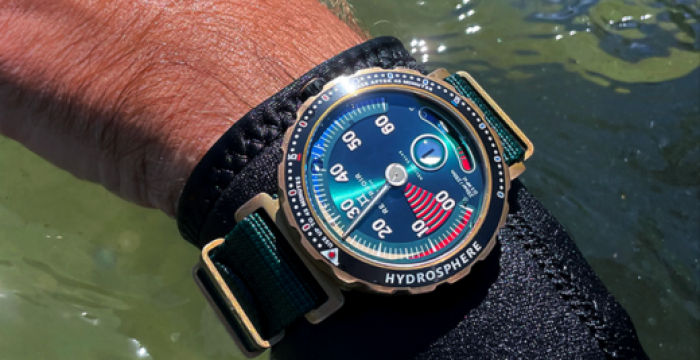 Close-up of a wrist wearing a blue-dial "Hydrosphere" diving watch near water, with a durable strap.