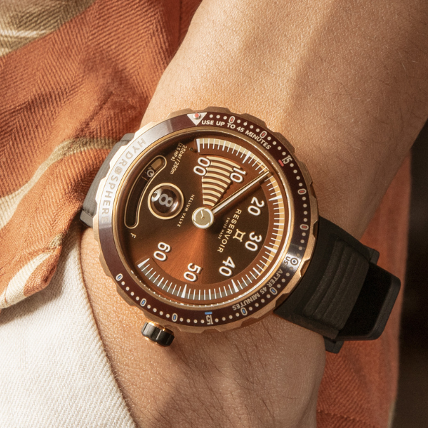 Bronze-dial wristwatch with semi-circular gauge, date window, marked bezel, black textured strap.