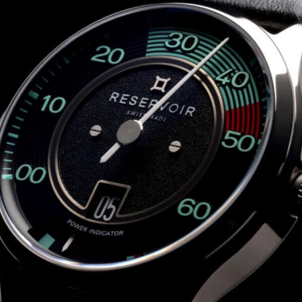 Close-up of a watch face with numeric indicators, text "RESERVOIR SWISS MADE," and a power indicator.