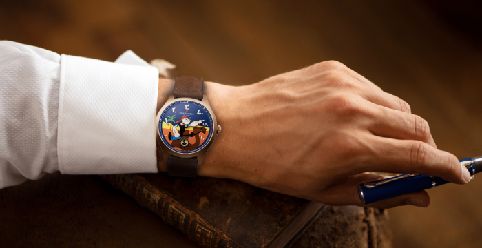 Wristwatch with a colorful design on a wrist wearing a white shirt, holding a blue pen by an old book.