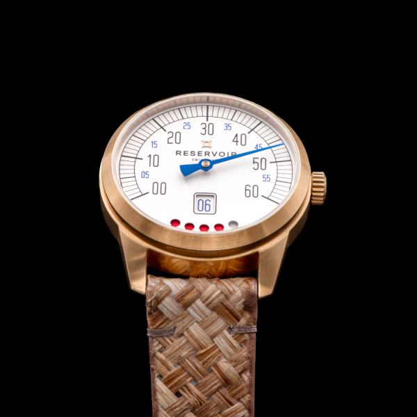 Luxury wristwatch with gold bezel, white dial, blue minute hand, date window, and woven strap.