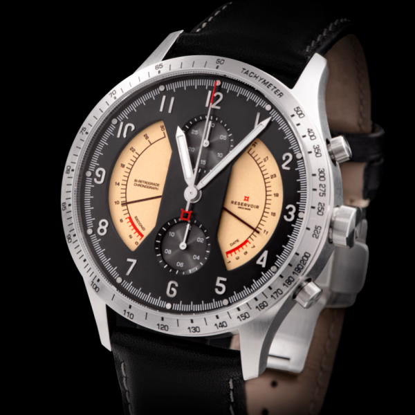 Luxury wristwatch with black dial, silver hands, tachymeter bezel, two beige subdials, leather strap.