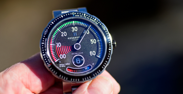 Montre métallique indiquant la réserve de marche avec lunette gravée indiquant les intervalles de secondes.