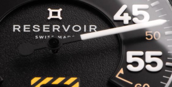 Detalle de la esfera de un reloj de pulsera Reservoir con números blancos, fecha e indicador de combustible.