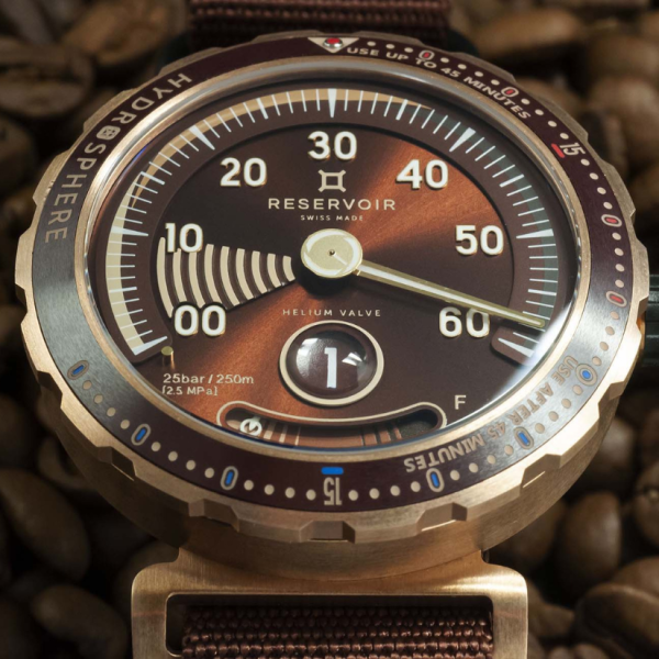 Reservoir wristwatch with brown dial, retrograde minute display, helium valve, and textured strap.