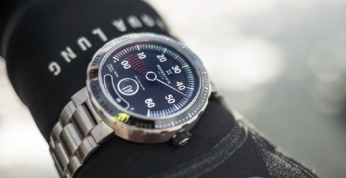 Silver wristwatch with black dial and white numerals on wrist, wearing "BA LUNG" diving suit.
