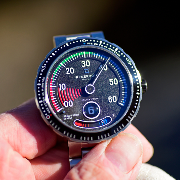 Close-up wristwatch with a black dial, stainless steel bracelet, and multiple colored indicators.