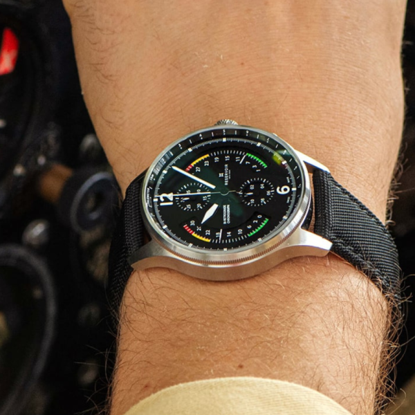 Wristwatch with black dial, subdials, numeric and color indicators, on black fabric strap, technical background