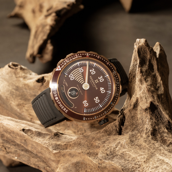 Wristwatch with brown dial and black strap on driftwood, showing bold numbers and date display.