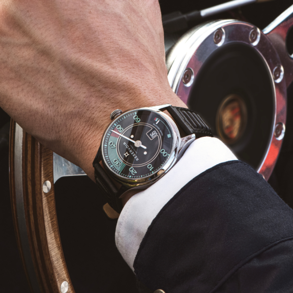 Person's wrist with a black-strap wristwatch grasping a wooden steering wheel inside a vehicle.